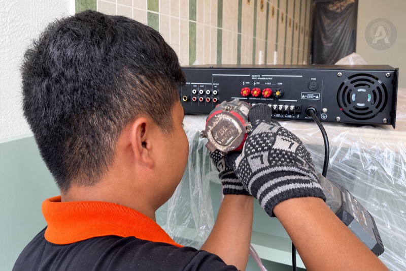 Kỹ thuật viên thao tác tại cụm đầu nối phía sau amply 100V